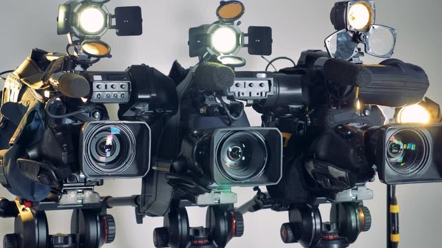 Three working video cameras in a slow rotating shot. 