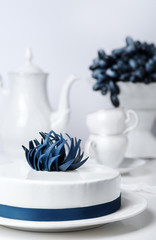 Holiday white mousse cake decorated with blue creative flower with tea set and grape on stand cake...