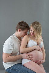 Beautiful pregnant couple in love on the background.Hands of husband on the tummy of his pregnant wife. Young man tenderly stroked pregnant belly of his wife. Husband kissing pregnant belly.