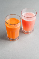 Two glasses of juice on grey background