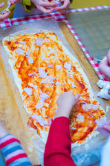 children are cooking pizza. hands in the frame
