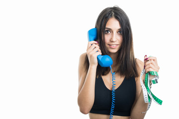 Fit girl talking on phone holding measuring tape