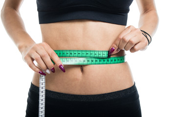 Close up of fit girl measuring waist with tape