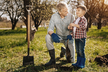 Delighted boy standing near his grandfather