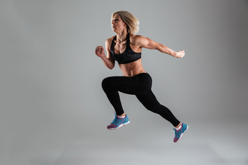 Fototapeta na wymiar Full length portrait of a strong muscular adult woman jumping