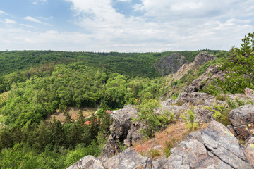 Fototapeta na wymiar Lush gorge viewed from the rocky top at the Divoka Sarka on a sunny day. It's a nature reserve on the outskirts of Prague in Czech Republic.