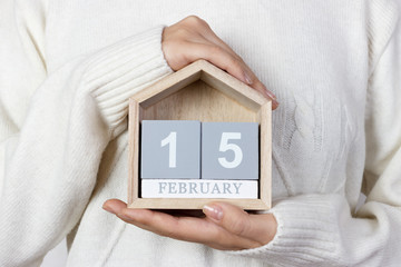 15February in the calendar. the girl is holding a wooden calendar. International Childhood Cancer Day, National Flag of Canada Day