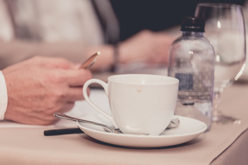 businesspeople hands with pen or pencil , papers and cups of coffee in the seminar room