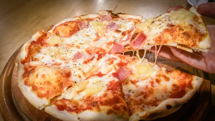 Hawaiian Pizza slice with cheese on a wooden table In the restaurant. Italian menu food traditional cuisine .