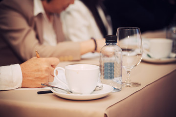 businesspeople hands with pen or pencil , papers and cups of coffee in the seminar room