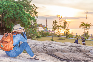 Women travelers happy traveling and taking photo with digital camera to the beauty of the city and the sea in his holidays During his time at sunset for Post to Online on the Internet.