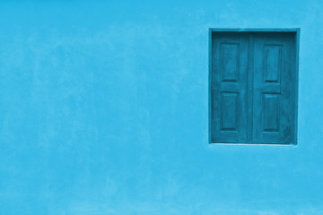 Light baby blue color facade with darker blue window and large empty blue wall texture background space.