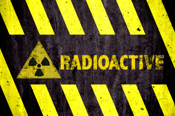 Radioactive (ionizing radiation) danger symbol and word with yellow and black stripes painted on a...
