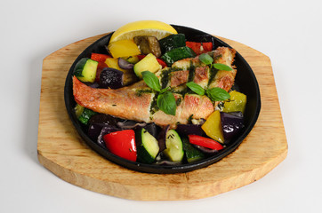 Red snapper baked with vegetables in a pan on a wooden desk