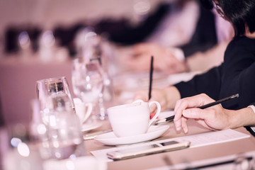 businesspeople hands with pen or pencil , papers and cups of coffee in the seminar room