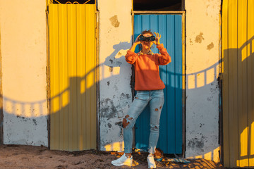 Young Girl Stands Near A Colorful Wall And Looks Through Binoculars