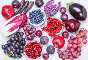 Assorted red and purple fruits and vegetables, berries top view.