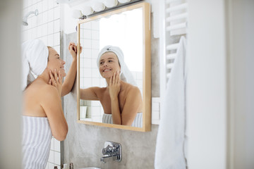 Woman Looking Herself in Bathroom Mirror
