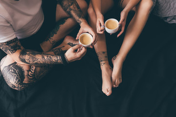 couple with cups of coffee in bed - obrazy, fototapety, plakaty