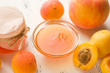 homemade jam of ripe peaches on a white wooden background