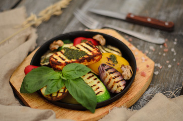 Vegetables grilled with cheese in a pan on a wooden desk