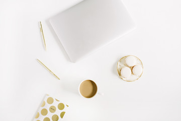 Modern gold stylized home office desk with laptop, macaroons, pen, coffee mug on white background. Flat lay, top view lifestyle concept.