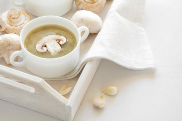 Fototapeta na wymiar Two bowl with traditional mushroom soup cream on white table cloth