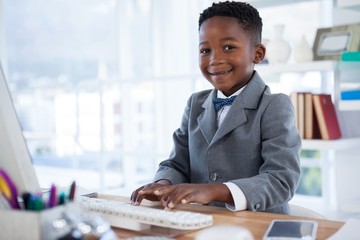 Portrait of boy imitating as businessman using computer - obrazy, fototapety, plakaty