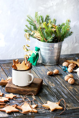 Homemade shortbread star shape sugar cookies different size in vintage mug and as garland on old wooden table decorated by Christmas tree and gifts. Christmas mood theme.