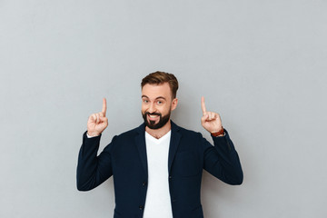 Happy bearded man in business clothes pointing up