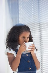 Businesswoman having coffee while standing by window