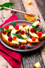 Grilled pumpkin with honey, raspberry and mint on wooden rustic background. Close up.