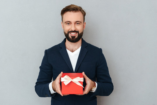 Smiling Bearded Man In Business Clothes Holding Gift