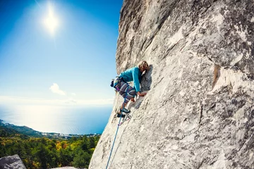 Tuinposter A rock climber on a wall. © zhukovvvlad