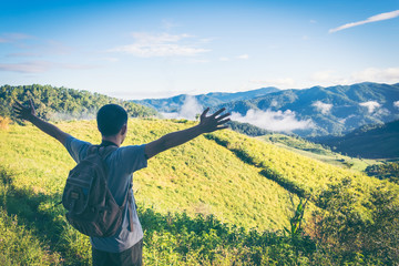 Mountain summit. Happy man gesture raised arms. Funny hiker with raised hands in the air on rock edge in national park. Vivid and strong vignetting effect.