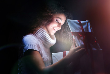 Excited cheerful attractive young woman opening gift over black 