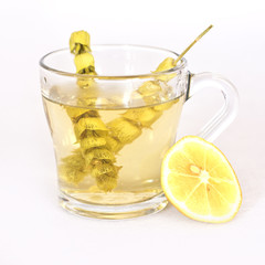 Hot tea with sage and lemon in a glass mug.