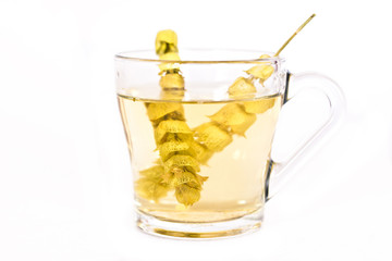 Hot tea with sage and lemon in a glass mug.