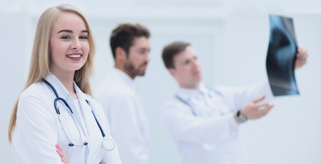 Doctor smiling at camera while his colleagues discussing in back