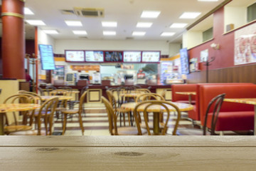 Cafe or restaurant, nobody of visitors. Defocused image. In the foreground is wooden table top.