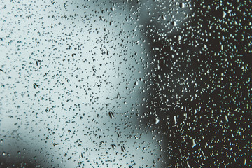 Naklejka na ściany i meble Wet window with water drops on a blurred background