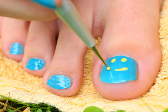teenager girl hand with enamel laque brush pedicure her toes foot with creative smile pattern