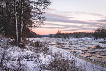 Fototapeta na wymiar Frozen river with ice flow. Purple sunset.