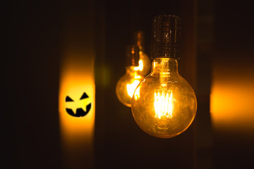 Light bulb closeup vintage retro style with halloween's face on a background
