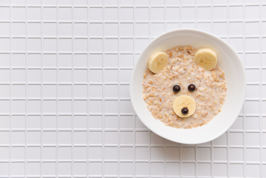 oatmeal porridge with fruit and berries. children's food with a bear face