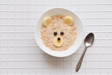 oatmeal porridge with fruit and berries. children's food with a bear face