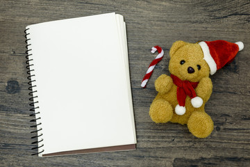 Christmas bear and white book with top view and copy space on the brown wooden table. Christmas festival concept.