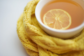 Mug of hot tea in a scarf on a window sill at a window
