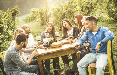 Happy friends having fun outdoor drinking red wine - Young people eating food at harvest time in farmhouse vineyard winery - Youth friendship concept with shallow depth of field - Warm contrast filter - obrazy, fototapety, plakaty