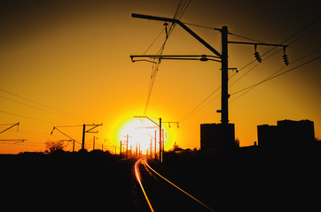 Railway - Railroad at sunset with sun, Rails and electric lines in yellow light